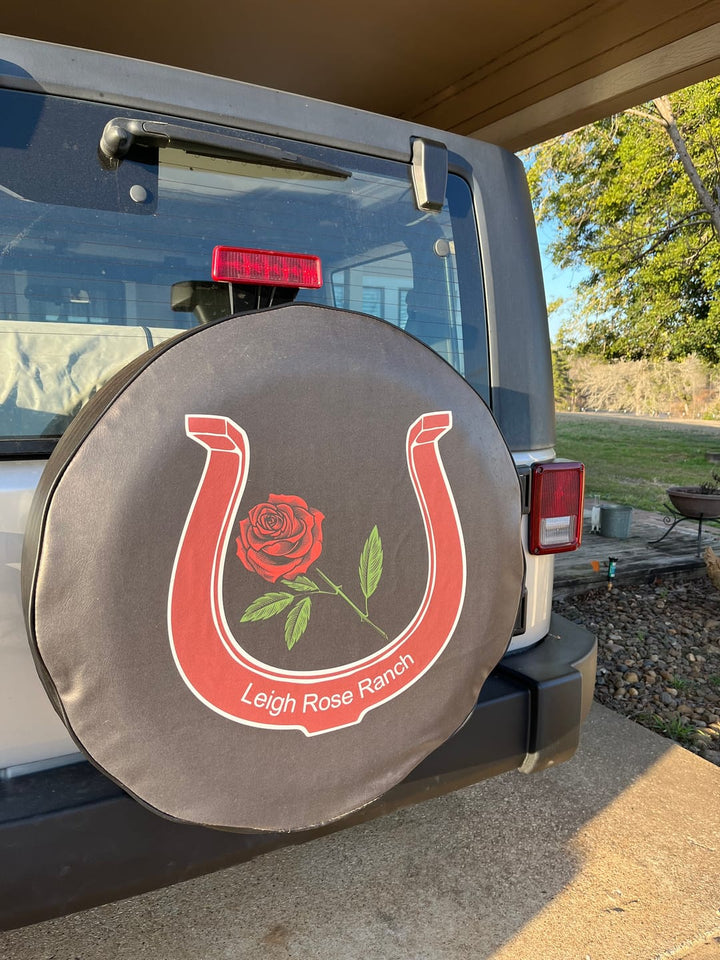 Tire cover with a horseshoe and rose design on a vehicle