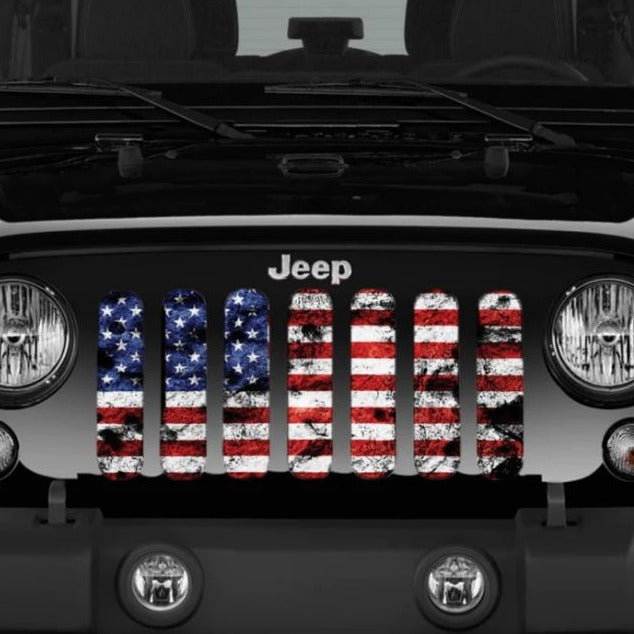 Close up view of a black Jeep Wrangler displaying a Jeep grille insert of an American flag in full color red white and blue with rustic dirty detail