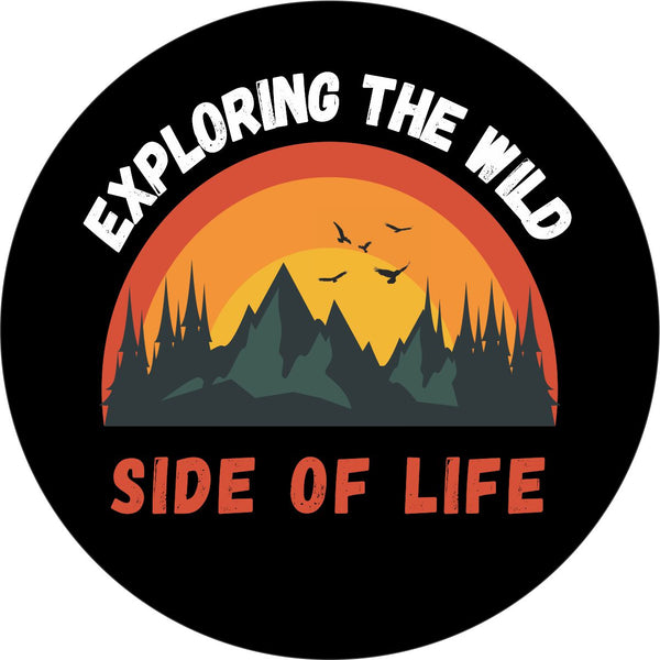 Mockup graphic design of a spare tire cover with the phrase exploring the wild side of life and a cute picture of mountains, trees, and birds flying. 