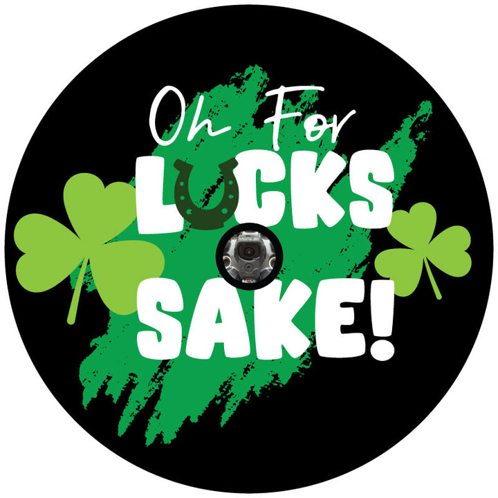 A mockup example design for a black vinyl spare tire cover with a hole for a backup camera and the saying :oh for lucks sake" and a green horseshoe upside down for the U in luck, plus green paint swatch and some green clovers or spades.