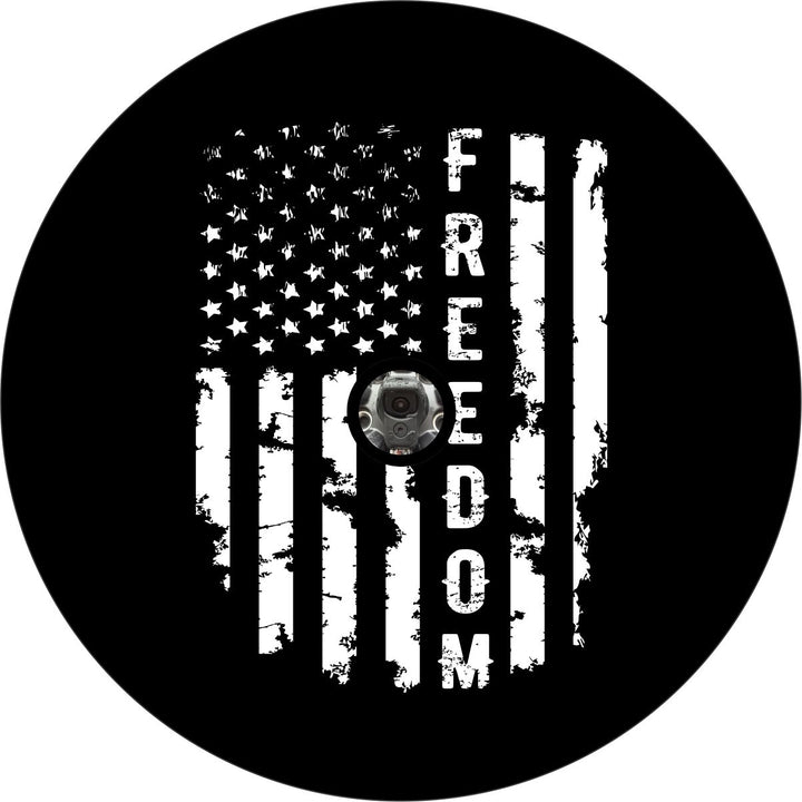 Black and white spare tire cover design of a vertical rustic looking American flag and the word freedom in place of one of the stripes written vertically down the flag with an opening for a back up camera.