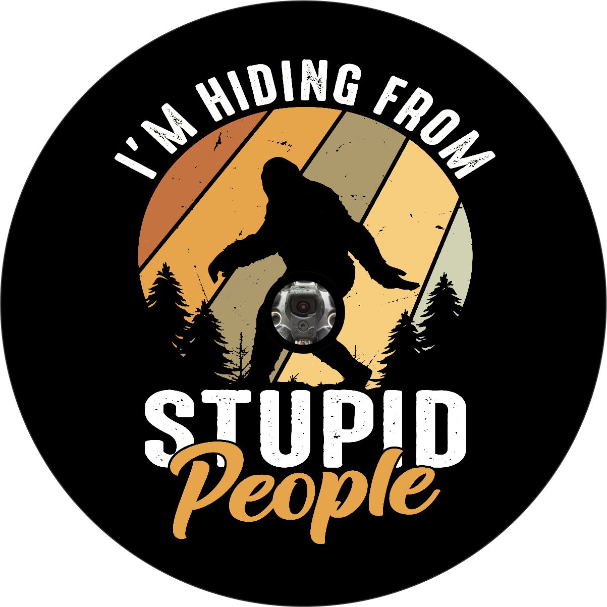 Vibrant and high quality vinyl spare tire cover made from orange and red earth tones with a silhouette of sasquatch and the saying, I'm hiding from stupid people with a camera hole for a backup camera.