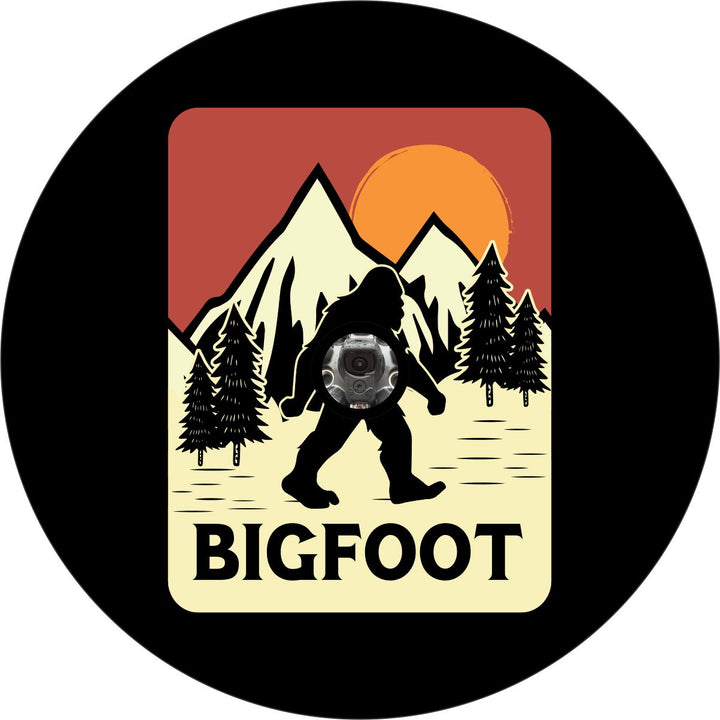 Creative bigfoot spare tire cover design with bigfoot walking along in a vintage poster design with mountains, red sky and orange sunset plus a camera hole for a spare wheel with back up camera.