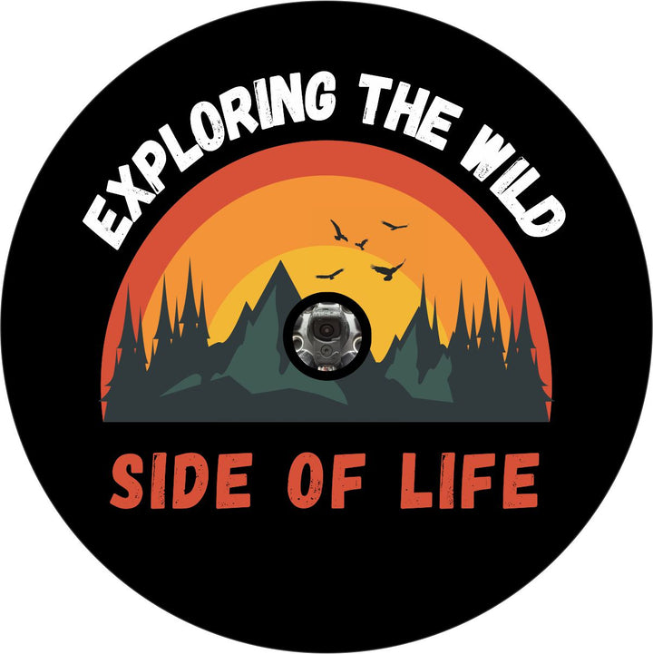 Mockup graphic design of a spare tire cover that can accomodate a backup camera with the phrase exploring the wild side of life and a cute picture of mountains, trees, and birds flying