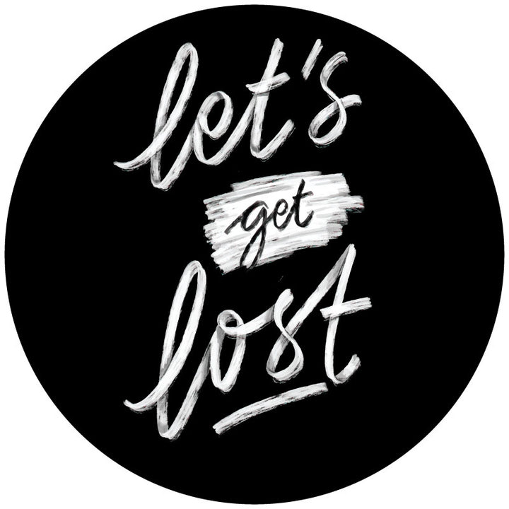 A mockup design of a black vinyl spare tire cover handwritten that says "Let's Get Lost" in cursive font in white. 