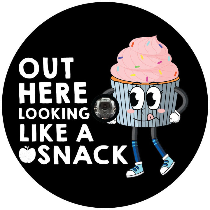 A unique spare tire cover design for a soft black vinyl spare tire cover with a cute pink cupcake character and the text or saying "out here looking like a snack" with a center hole to accommodate a spare tire with a backup camera.