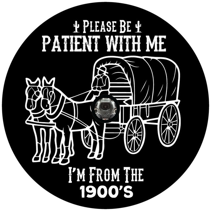 A spare tire cover design for an external spare wheel with a backup camera that says please be patient with me I'm from the 1900's and a silhouette of a covered wagon and horses.