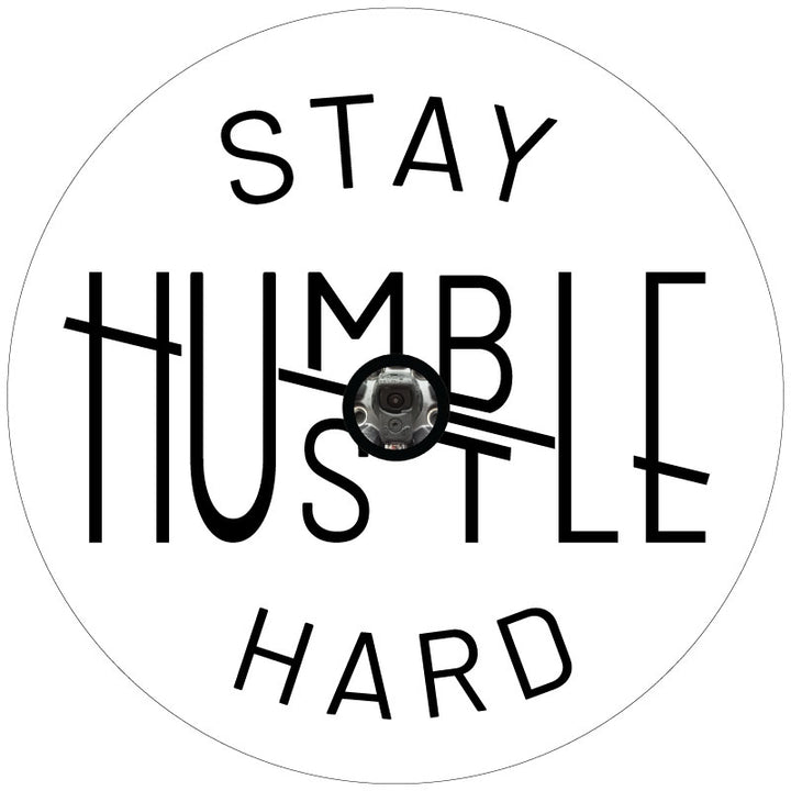 A spare tire cover design for a Jeep, Bronco, RV, camper, van, etc. with a unique design play on the words stay humble hustle hard with black text meant for white vinyl and a backup camera hole.