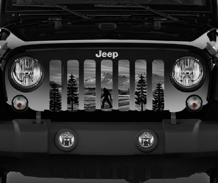 Close view of a Jeep grille insert of Sasquatch walking through the woods and mountains