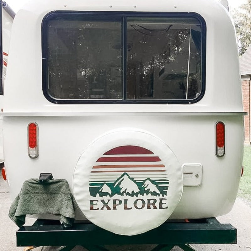 Custom white vinyl Explore spare tire cover on a white camper van