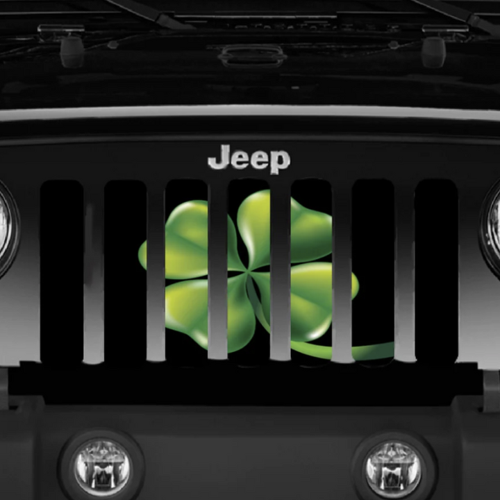 Up close view of a black Jeep Wrangler displaying a green four leaf clover shamrock designed Jeep grille insert