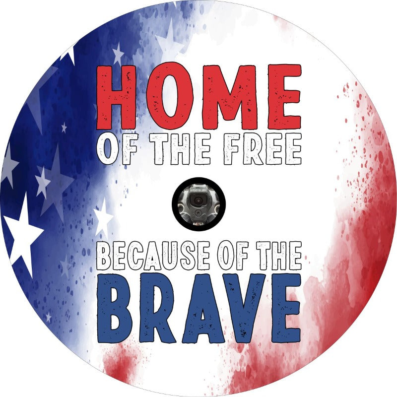 Spare tire cover with home of the free because of the brave in bubble letter font set on the background of a tie dye red, white, and blue patriotic background with a space for a JL back up camera