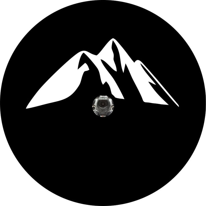 Mockup design of a black vinyl spare tire cover with a camera hole for an RV, camper, Jeep, trailer, Bronco, van, motorcoach or any other vehicle with an external spare wheel that has a backup camera. Design is a simple mountain silhouette graphic