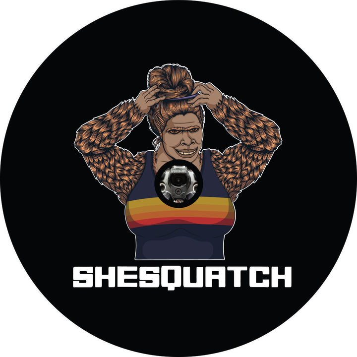 Shesquatch putting her hair in a top knot messy bun black vinyl custom spare tire cover with a JL back up camera design 