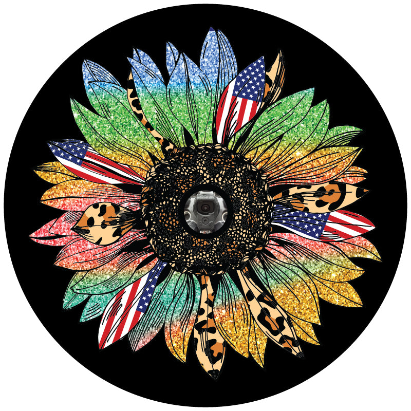 A sunflower spare tire cover with rainbow sparkle petals, American flag petals, and cheetah print or leopard print animal print petals. This design is displayed to show the sunflower on a black vinyl spare tire cover with a JL back up camera accommodation.